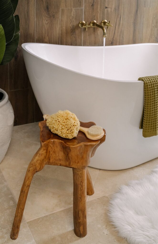 Primary bathroom designed by Rachel Jackson Design with a freestanding tub and wood accent wall, featured in Good Housekeeping May/Jun '26